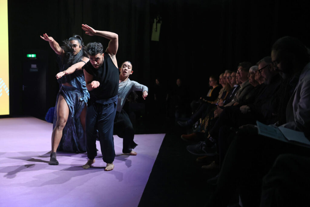 Three dancers moving on stage.