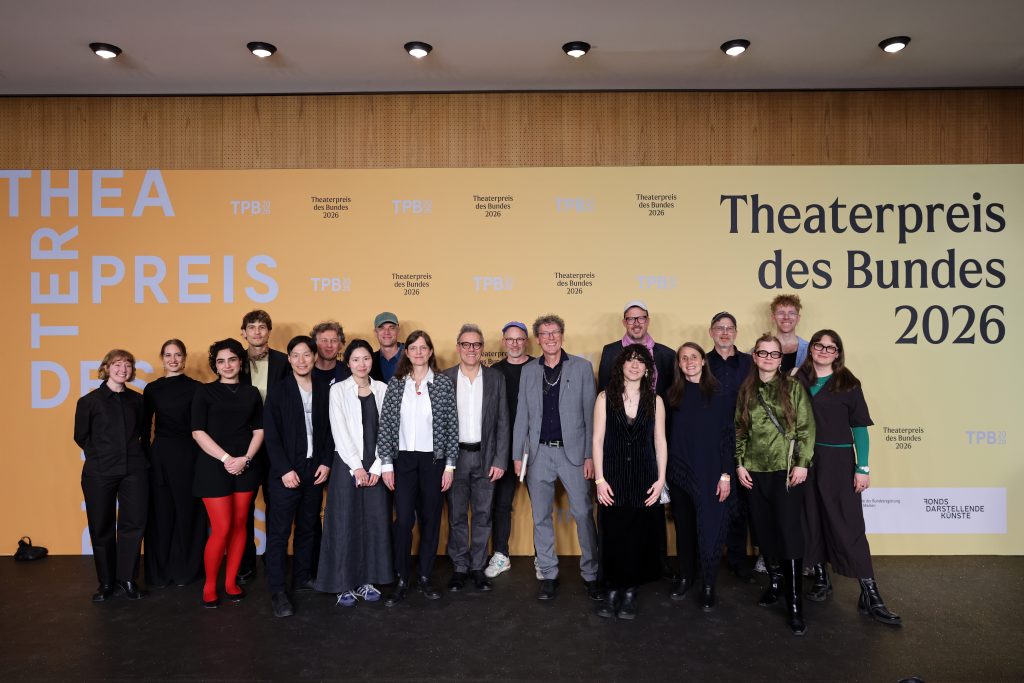 Das Team steht vor einer Fotowand mit dem Aufdruck: Theaterpreis des Bundes 2026.