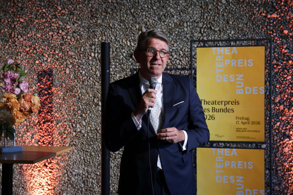 Wolfram Weimer steht vor einem Plakat mit der Aufschrift 